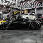 A sleek black sports car and luxury vehicles in a high-end auto repair shop interior.